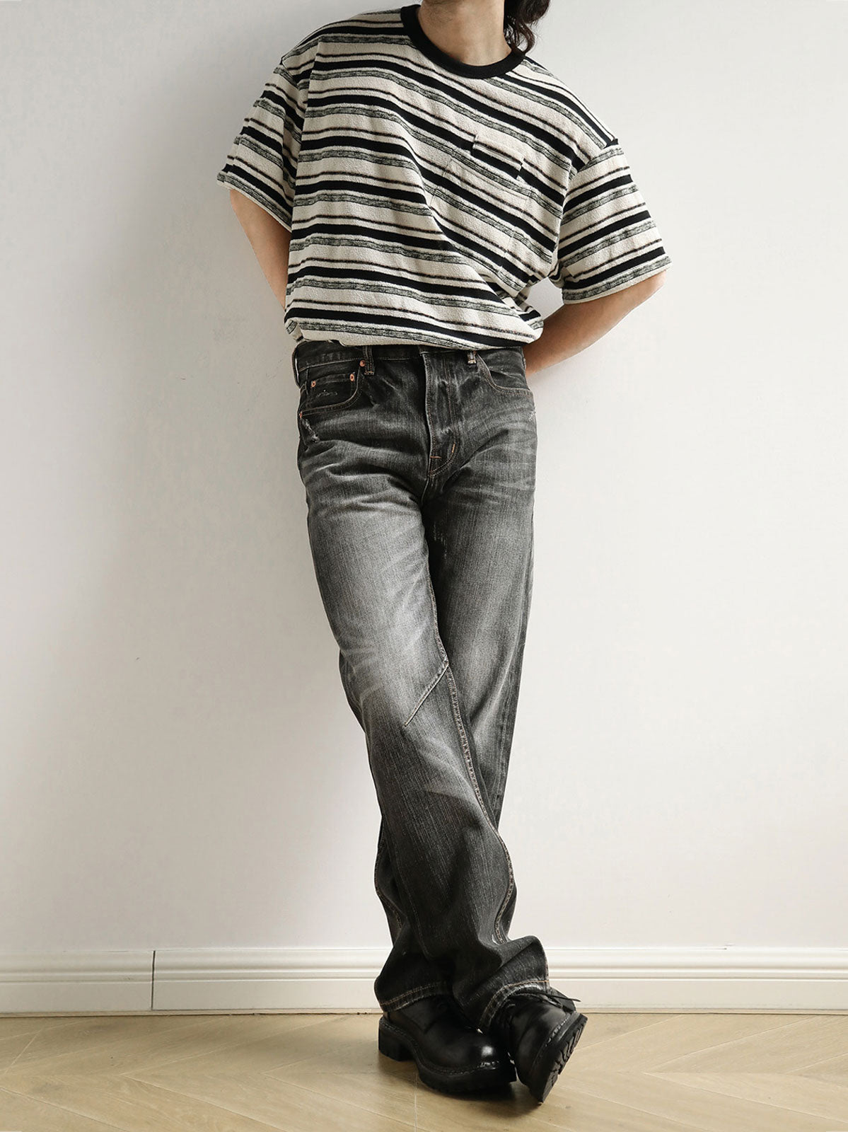 モデルがブラック&ホワイト・ストライプ・ショートスリーブTシャツを着用し、その全体的なスタイルとフィット感を示しています
