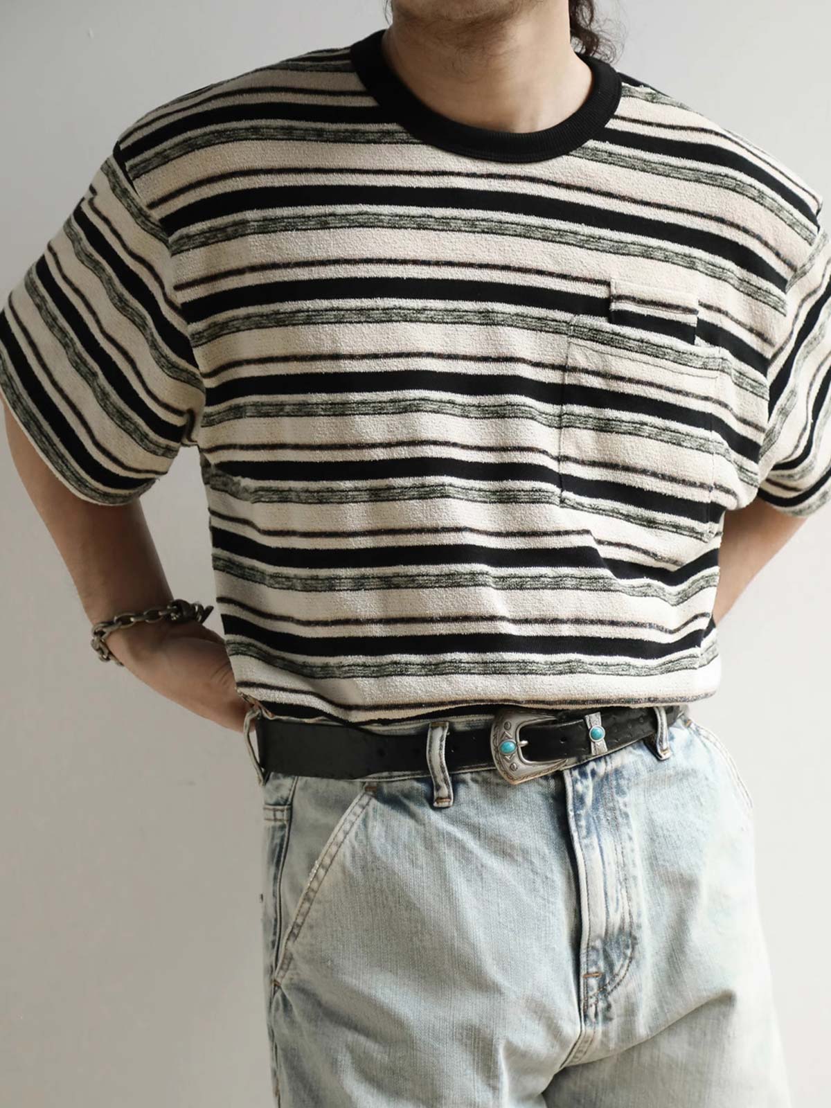 モデルがブラック&ホワイト・ストライプ・ショートスリーブTシャツを着用し、その全体的なスタイルとフィット感を示しています