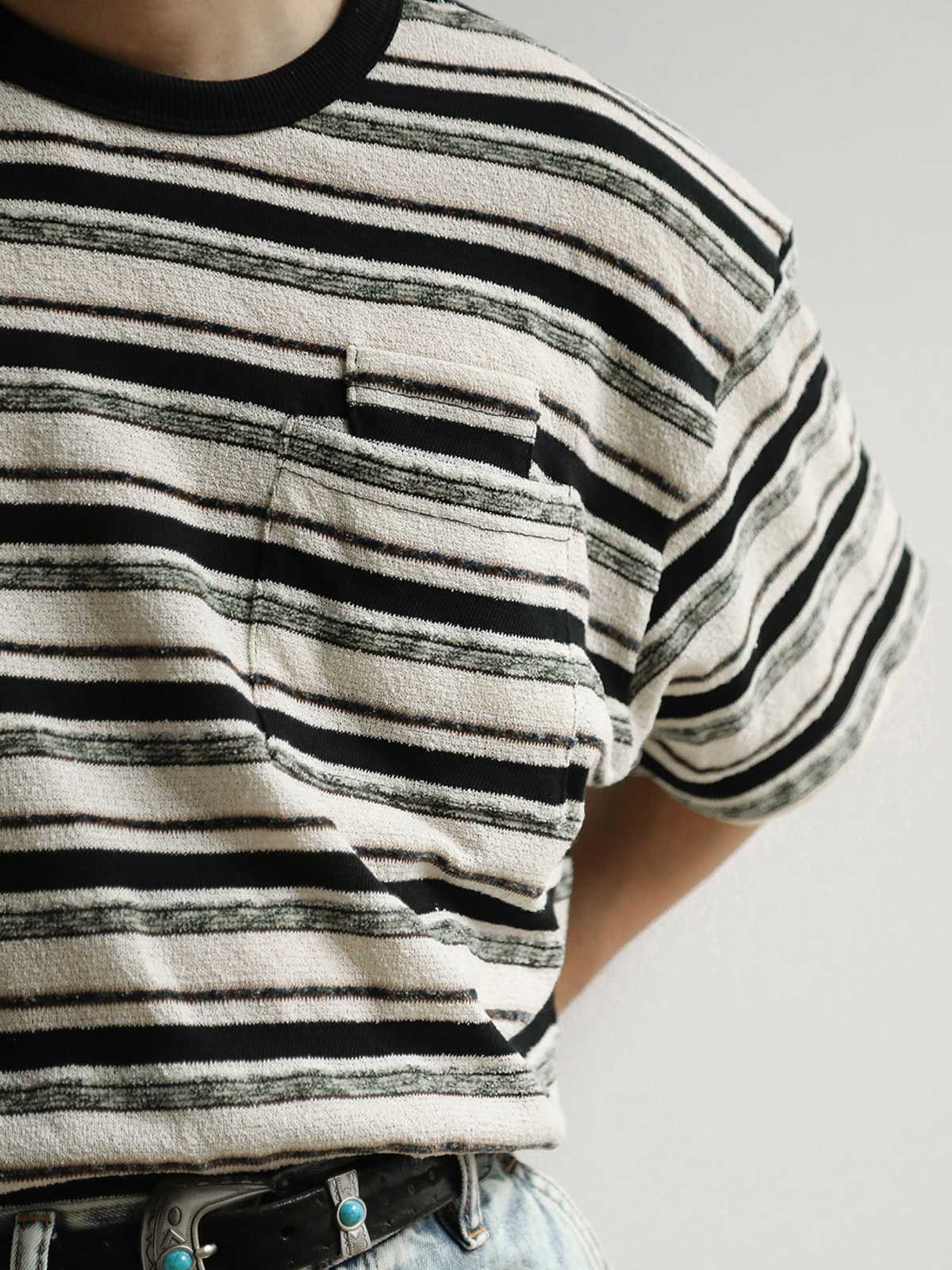 モデルがブラック&ホワイト・ストライプ・ショートスリーブTシャツを着用し、その全体的なスタイルとフィット感を示しています