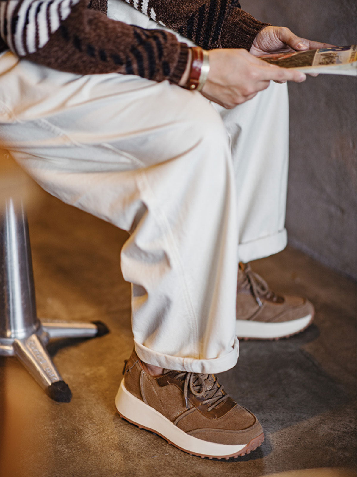 詳細画像:
「厚底スニーカーのディテールクローズアップ。牛革スエードとクレイジーホースレザーを使用した異素材パッチワークが高級感を演出し、丁寧なステッチワークがクラシックデザインを引き立てます。サンドカラー配色が70年代OGスタイルの魅力を際立たせています。」
モデル画像:
「モデルが70年代OGスタイル 厚底スニーカーを着用し、サンドカラー配色と立体感ある異素材デザインが際立つカジュアルコーディネートを披露。3.5cm厚のラバーソールが快適な履き心地とスタイルアップ効果を提供します。」