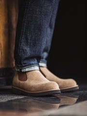 詳細画像:
チェルシーブーツのゴムバンドとスエードの質感がクローズアップされたディテール画像。履きやすさとデザインの美しさが強調されています。
モデル画像:
モデルがライトブラウンスエードチェルシーブーツを履いたスタイル。カジュアルからワークスタイルまで、多様なコーディネートに対応可能なアイテムです。