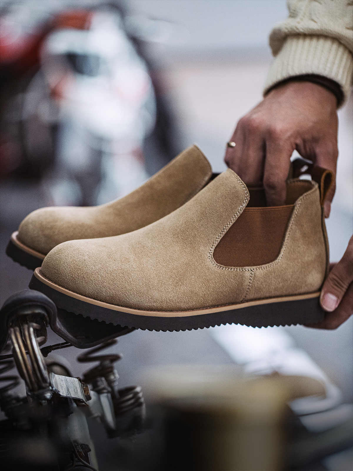 製品画像:
ライトブラウンのスエードチェルシーブーツ全体画像。シンプルで洗練されたデザインが特徴で、秋冬シーズンに最適なスタイルを提案します。
詳細画像:
チェルシーブーツのゴムバンドとスエードの質感がクローズアップされたディテール画像。履きやすさとデザインの美しさが強調されています。