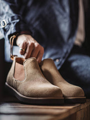 製品画像:
ライトブラウンのスエードチェルシーブーツ全体画像。シンプルで洗練されたデザインが特徴で、秋冬シーズンに最適なスタイルを提案します。
詳細画像:
チェルシーブーツのゴムバンドとスエードの質感がクローズアップされたディテール画像。履きやすさとデザインの美しさが強調されています。