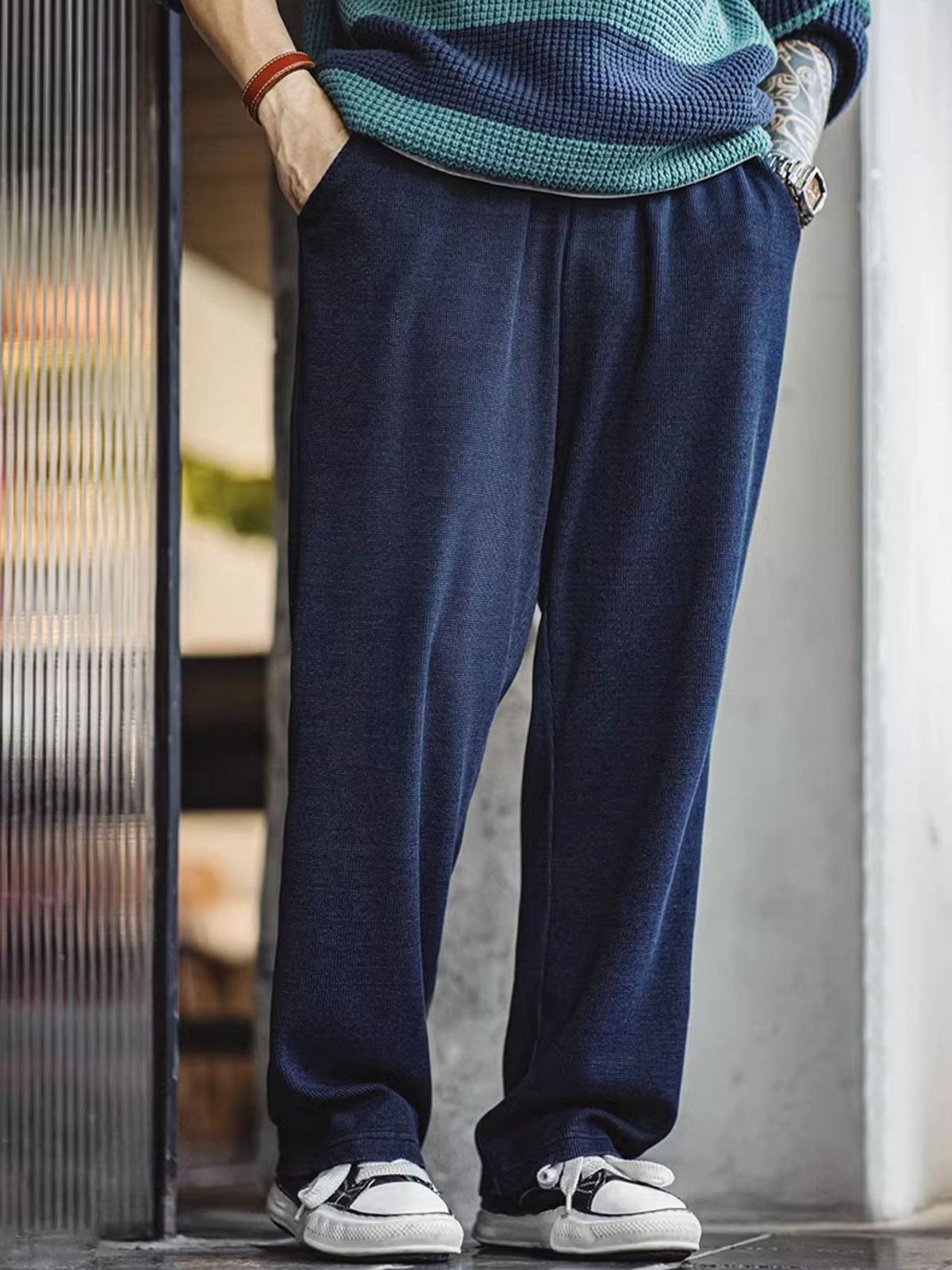 製品画像: ワッフルニットドレープ効果付きカジュアルパンツ正面図
詳細画像: パンツのディテール、白い編み込みドローストリングと石風ビーズ