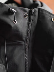 製品画像: 三つポケット撥水性フード付きテクニカルジャケット 正面、アウトドアから都市通勤まで対応
詳細画像: グロメットジッパーとレインシェルデザインのディテール、防護性能