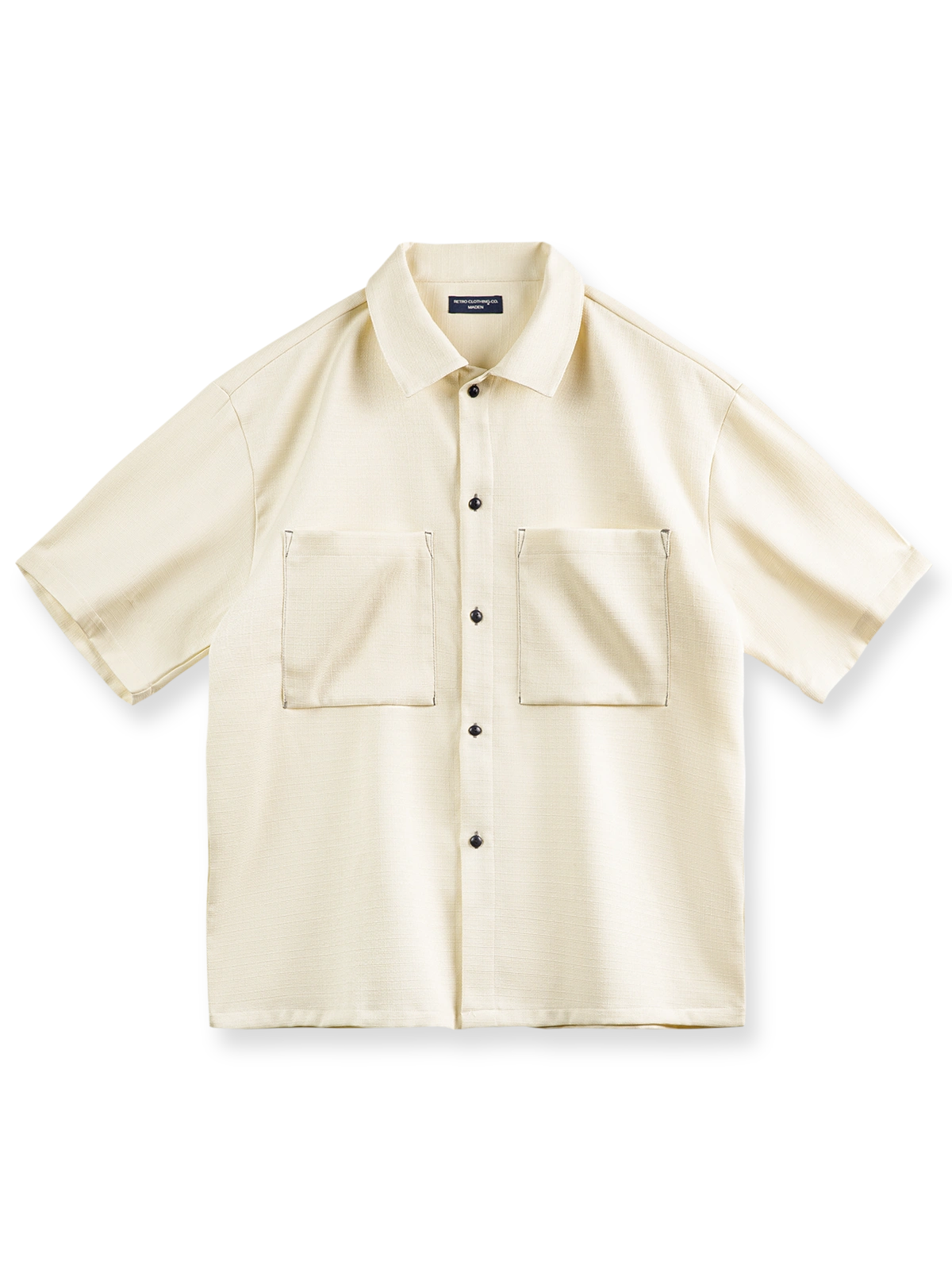 透明感のある竹節平織りテクスチャのオーバーサイズ半袖シャツの正面ビュー。リラックスフィットでエレガントなドレープを特徴とし、実用的な大型スクエアポケットがデザインアクセントです。