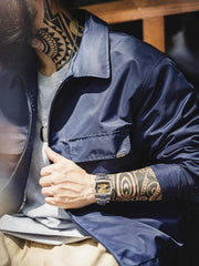 詳細画像
「背面に施された『Hustle is Mentality』スローガンとダイヤモンド型チェーン刺繍のディテール写真。クラシックなデザインと挑戦者の精神を象徴するヴィンテージスタイルのジャケット。」
モデル画像
「モデルがミッドナイトネイビー刺繍ワークジャケットを着用し、防風性のあるコントラストリブ裾やレトロなデザインを活かしたストリートスタイルを披露する写真。」