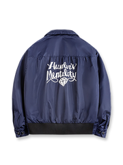 製品画像
「ミッドナイトネイビーのヴィンテージ感あふれる軽量刺繍ワークジャケット正面展示写真。150gナイロン素材とクラシックなフレーザータータンチェック裏地を組み合わせた秋冬の個性的な一着。」
詳細画像
「背面に施された『Hustle is Mentality』スローガンとダイヤモンド型チェーン刺繍のディテール写真。クラシックなデザインと挑戦者の精神を象徴するヴィンテージスタイルのジャケット。」