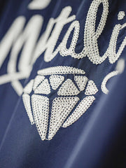 製品画像
「ミッドナイトネイビーのヴィンテージ感あふれる軽量刺繍ワークジャケット正面展示写真。150gナイロン素材とクラシックなフレーザータータンチェック裏地を組み合わせた秋冬の個性的な一着。」
詳細画像
「背面に施された『Hustle is Mentality』スローガンとダイヤモンド型チェーン刺繍のディテール写真。クラシックなデザインと挑戦者の精神を象徴するヴィンテージスタイルのジャケット。」