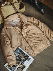 製品画像: レトロ風テーラード襟厚手中綿ジャケットのフロントビュー。防風・防寒機能付きの秋冬用アウター
詳細画像: ブロンズカラーのジッパーとテーラード襟のディテール。スタンドカラーとリフレクター付きロゴで機能性を強化