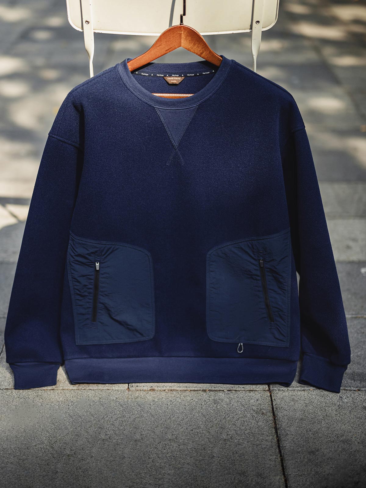 製品画像
「アメリカンヴィンテージ風デザインのウール混クルーネックスウェット全体展示写真。450~460g/m²のヘビーメルトン風ウール混素材を採用し、保温性と実用性を兼ね備えたネイビーカラーの秋冬に最適な一着。」
詳細画像
「アウトドアスタイルを取り入れた斜め配置のパッチポケットと、冷気の侵入を防ぐリブ袖口のディテール写真。高密度ウール混素材の質感と実用的なデザインが際立つスウェット。」