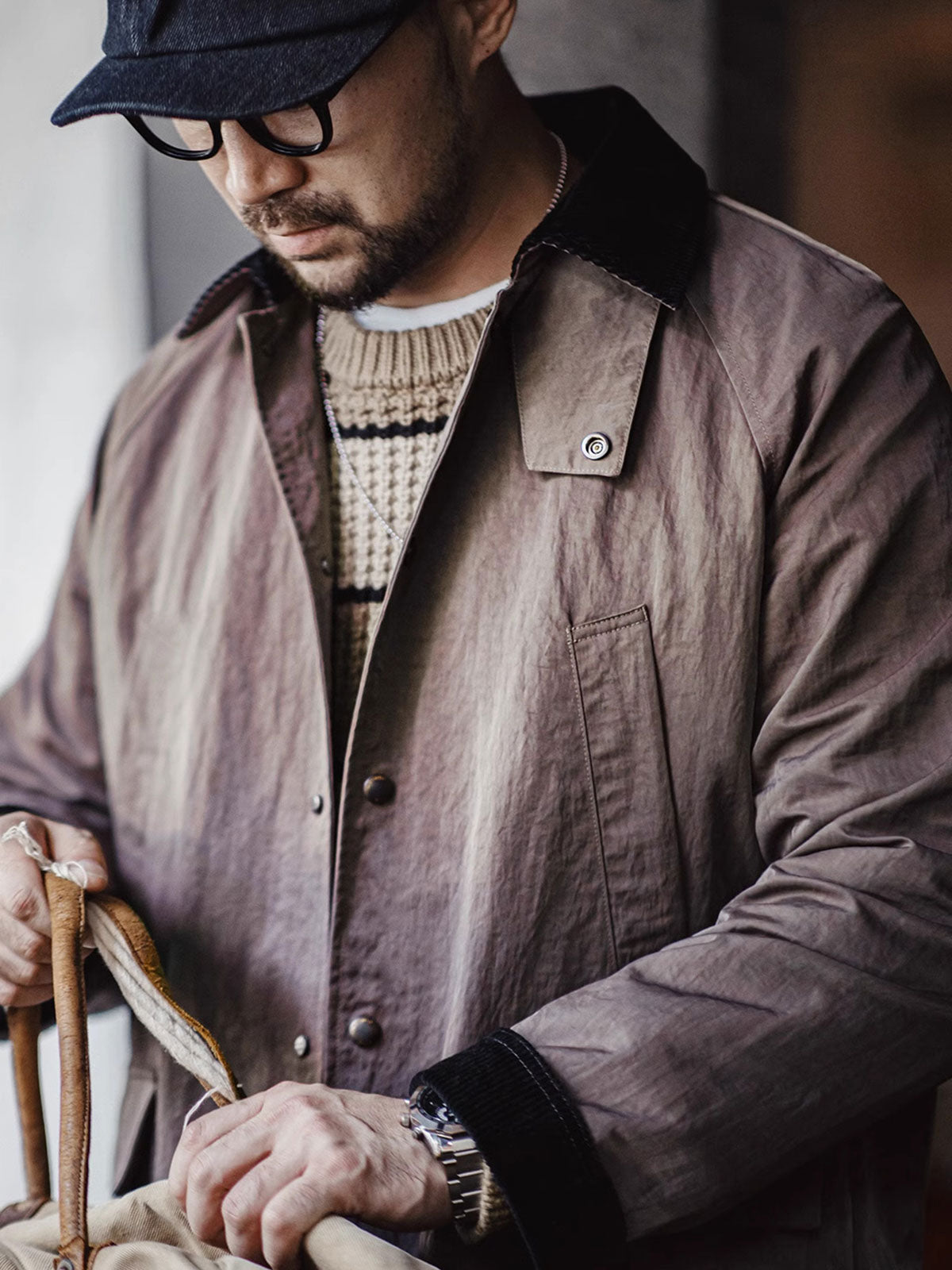 詳細画像:イギリスチェックの裏地と黒のコーデュロイラペルのディテール展示。クラシックなアクセントがコート全体に深いインプレッションをもたらす。
モデル画像:モデルがオーバーサイズのレトロハンティング風コートを着用し、袖口を巻き上げたスタイル。ブーツと合わせてアメリカンワークテイストを演出。