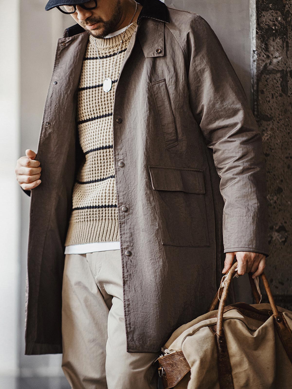 詳細画像:イギリスチェックの裏地と黒のコーデュロイラペルのディテール展示。クラシックなアクセントがコート全体に深いインプレッションをもたらす。
モデル画像:モデルがオーバーサイズのレトロハンティング風コートを着用し、袖口を巻き上げたスタイル。ブーツと合わせてアメリカンワークテイストを演出。