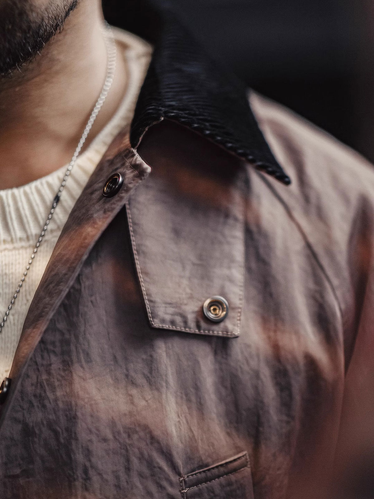 詳細画像:イギリスチェックの裏地と黒のコーデュロイラペルのディテール展示。クラシックなアクセントがコート全体に深いインプレッションをもたらす。
モデル画像:モデルがオーバーサイズのレトロハンティング風コートを着用し、袖口を巻き上げたスタイル。ブーツと合わせてアメリカンワークテイストを演出。