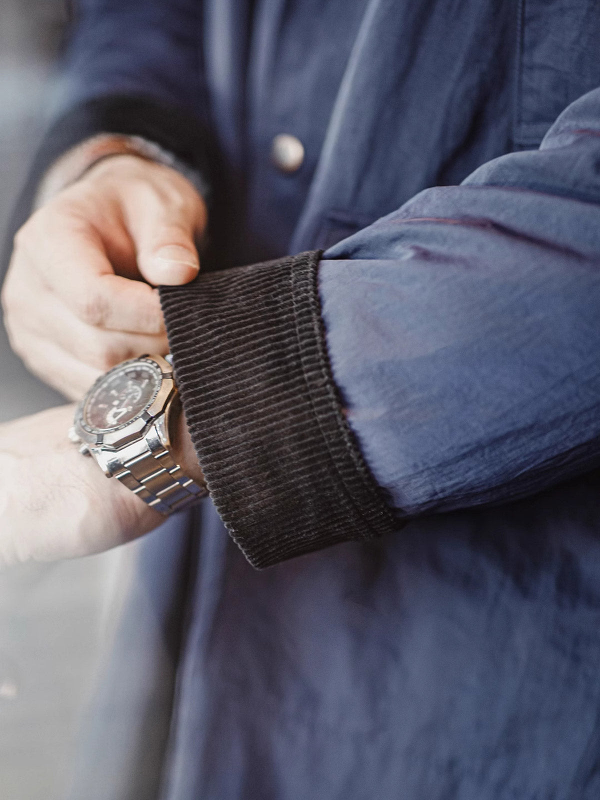 詳細画像:イギリスチェックの裏地と黒のコーデュロイラペルのディテール展示。クラシックなアクセントがコート全体に深いインプレッションをもたらす。
モデル画像:モデルがオーバーサイズのレトロハンティング風コートを着用し、袖口を巻き上げたスタイル。ブーツと合わせてアメリカンワークテイストを演出。