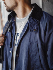 詳細画像:イギリスチェックの裏地と黒のコーデュロイラペルのディテール展示。クラシックなアクセントがコート全体に深いインプレッションをもたらす。
モデル画像:モデルがオーバーサイズのレトロハンティング風コートを着用し、袖口を巻き上げたスタイル。ブーツと合わせてアメリカンワークテイストを演出。