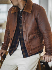 詳細画像:七つボタンの前立てと厚手のシープスキン襟のディテールをクローズアップ。ヴィンテージ感と実用性を兼ね備えた仕様。
モデル画像:モデルがムートンボマージャケットを着用し、デニムパンツとワークブーツを合わせたハードなバイカースタイルを提案。