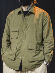 詳細画像
マットな5本爪スナップボタンと、戦地カメラマンの実用性を考慮して配置された3つのフラップ付きポケットのディテール特写。独自のシワ加工が施され、経年変化を楽しめる仕上がり
モデル画像
ノマドジャーナリストシャツを着用したコーディネート例。肩幅にゆとりを持たせたルーズフィットデザインが、ミリタリースタイルと現代的なワークウェアとしての快適さを融合したスタイリングを演出