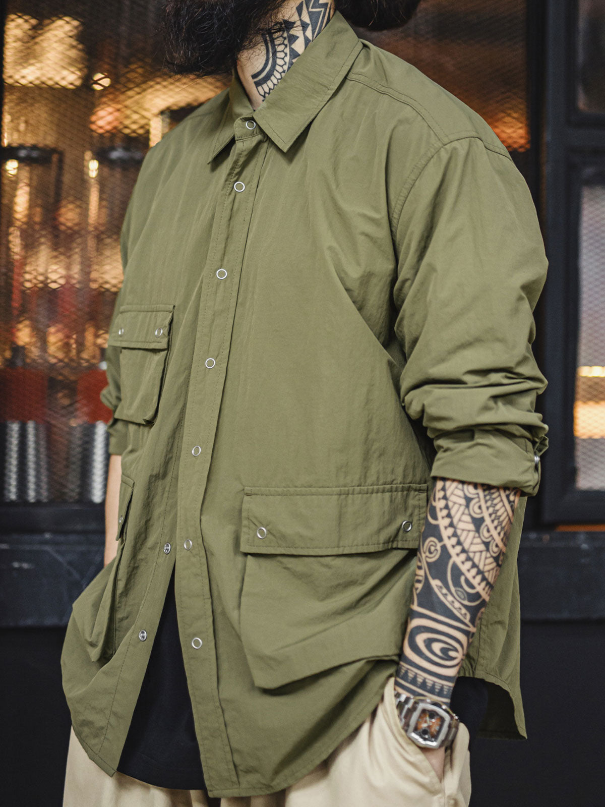 詳細画像
マットな5本爪スナップボタンと、戦地カメラマンの実用性を考慮して配置された3つのフラップ付きポケットのディテール特写。独自のシワ加工が施され、経年変化を楽しめる仕上がり
モデル画像
ノマドジャーナリストシャツを着用したコーディネート例。肩幅にゆとりを持たせたルーズフィットデザインが、ミリタリースタイルと現代的なワークウェアとしての快適さを融合したスタイリングを演出