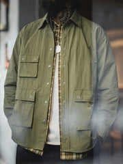 詳細画像
マットな5本爪スナップボタンと、戦地カメラマンの実用性を考慮して配置された3つのフラップ付きポケットのディテール特写。独自のシワ加工が施され、経年変化を楽しめる仕上がり
モデル画像
ノマドジャーナリストシャツを着用したコーディネート例。肩幅にゆとりを持たせたルーズフィットデザインが、ミリタリースタイルと現代的なワークウェアとしての快適さを融合したスタイリングを演出