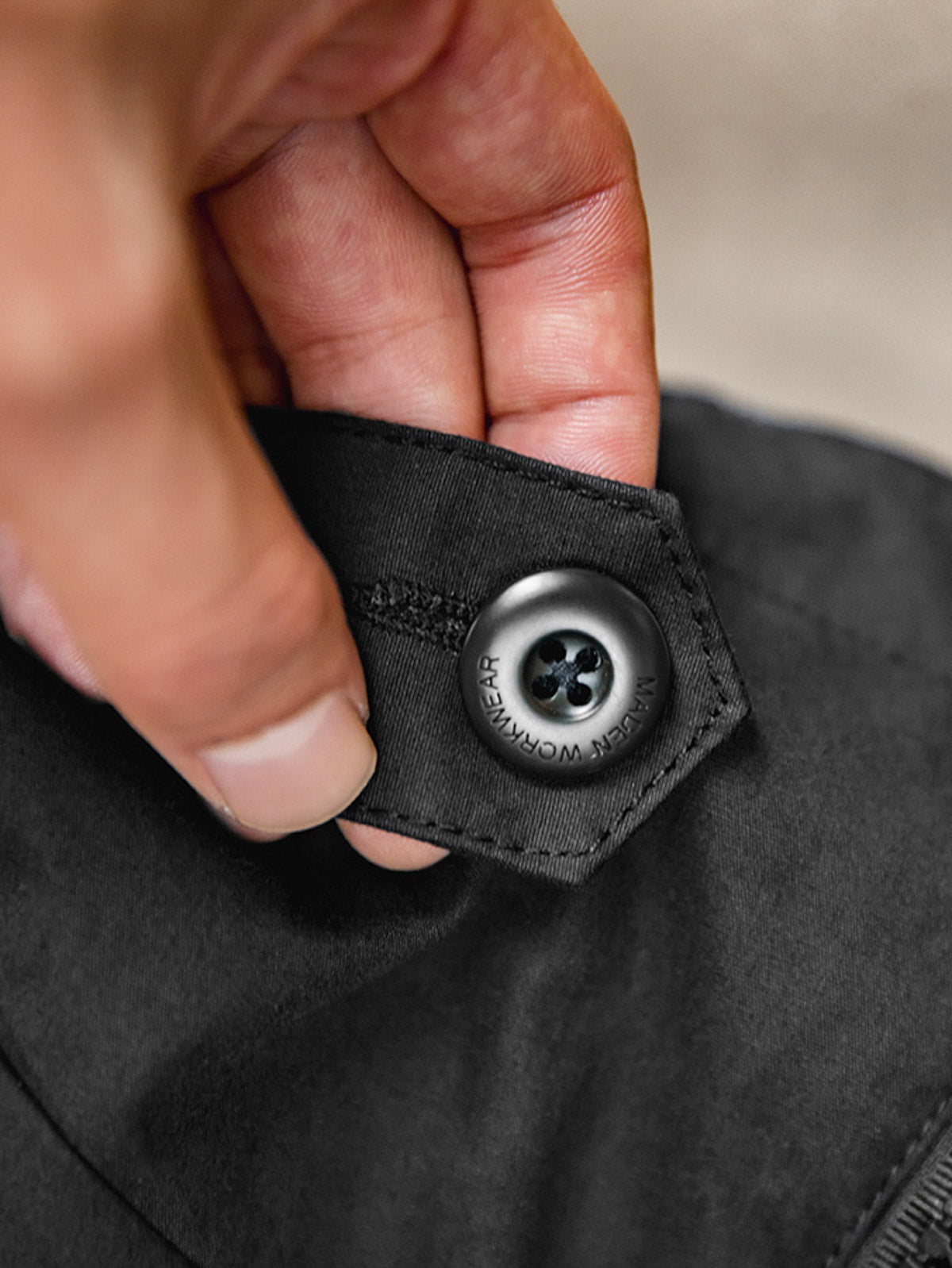 製品画像: 軽量で機能的なフード付きナイロンコートの正面ビュー。ECWCS風のデザインで、アウトドアや通勤にも最適な防護性と耐久性を兼ね備えた一着
詳細画像: ドローコード付きのフードと左側の機能ポケット、スナップボタンが付いた斜めポケットのディテール。ダブルジップ仕様で実用性を強化