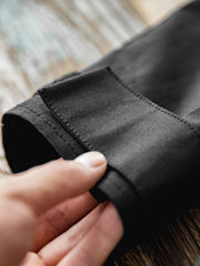 製品画像: 軽量で機能的なフード付きナイロンコートの正面ビュー。ECWCS風のデザインで、アウトドアや通勤にも最適な防護性と耐久性を兼ね備えた一着
詳細画像: ドローコード付きのフードと左側の機能ポケット、スナップボタンが付いた斜めポケットのディテール。ダブルジップ仕様で実用性を強化