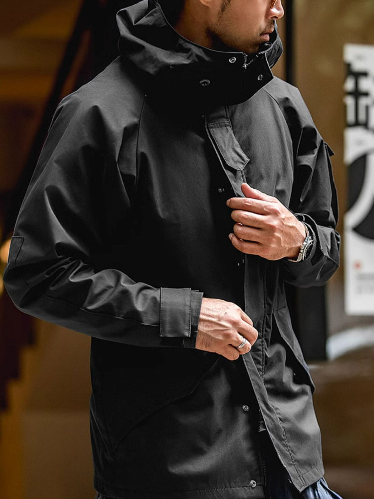 詳細画像: ドローコード付きのフードと左側の機能ポケット、スナップボタンが付いた斜めポケットのディテール。ダブルジップ仕様で実用性を強化
モデル画像: モデルが着用した機能性ナイロンコートの全身スタイリング。秋のデイリースタイルに合わせたルーズフィットで、アウトドアや通勤に適したコート