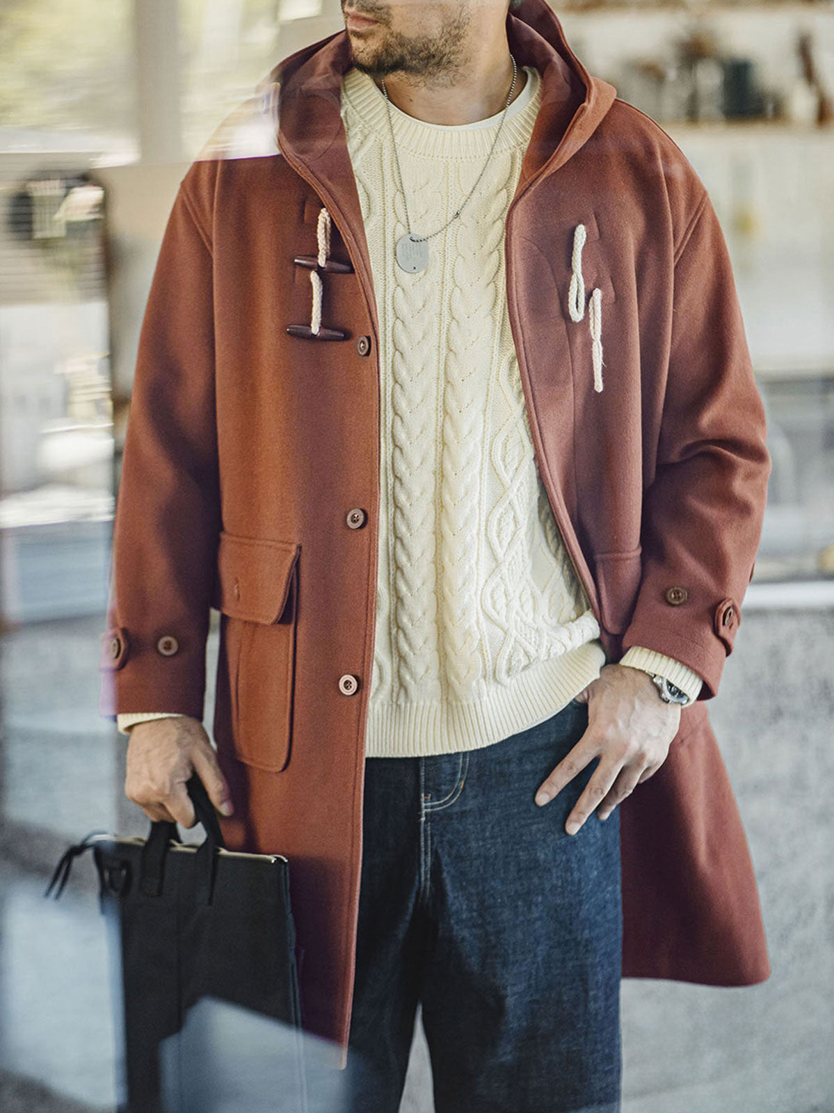 詳細画像:木製の牛角ボタンとアコーディオンポケットのディテールをクローズアップ。クラシックなディテールが、全体の完成度を高めています。
モデル画像:モデルがダッフルコートを着用し、学院風スタイルのカジュアルな冬のコーディネートを提案。