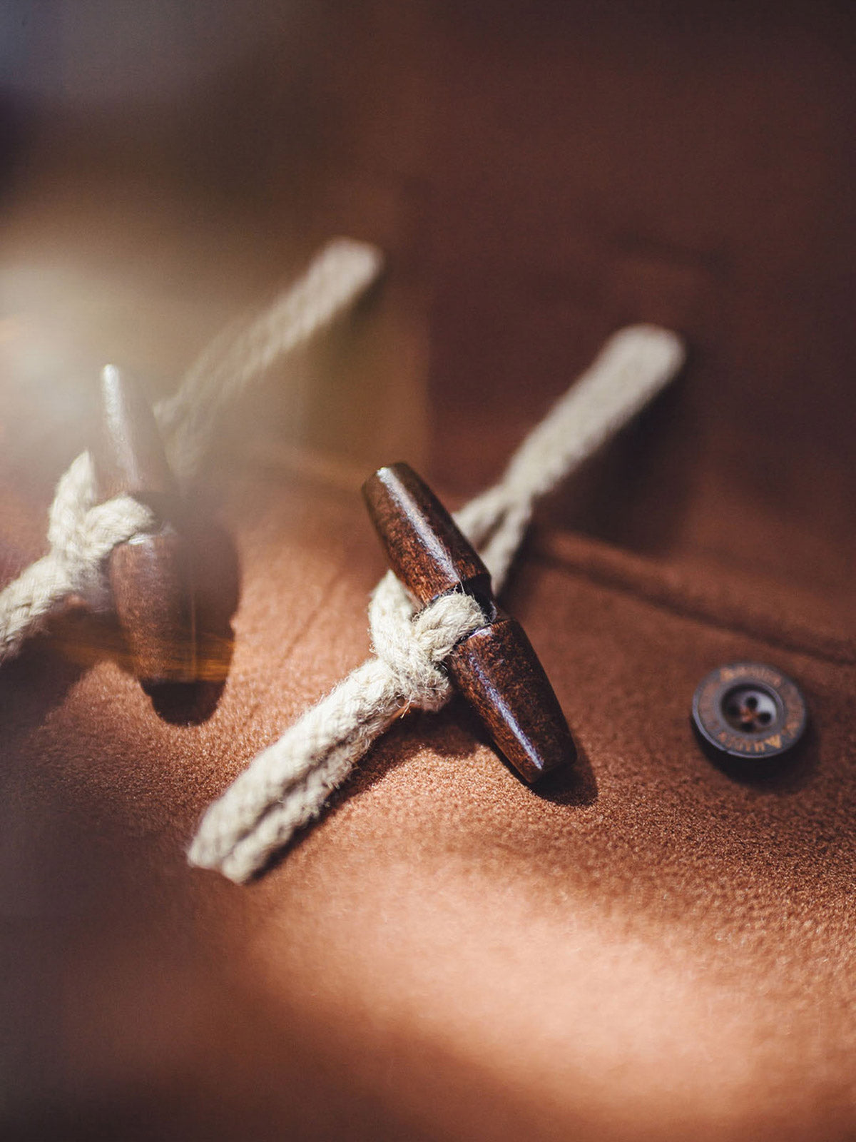 詳細画像:木製の牛角ボタンとアコーディオンポケットのディテールをクローズアップ。クラシックなディテールが、全体の完成度を高めています。
モデル画像:モデルがダッフルコートを着用し、学院風スタイルのカジュアルな冬のコーディネートを提案。