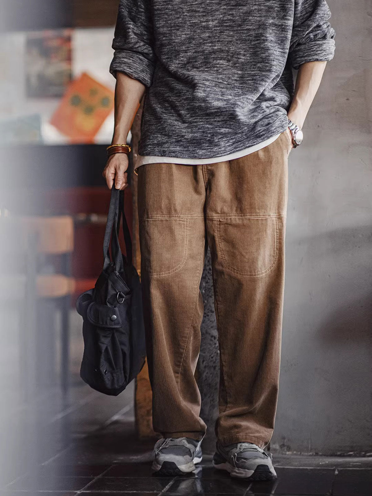 詳細画像: 木目調ボタンや多ポケットデザインのディテール表示。アンティーク風のメタルタグや異なるベルトループの幅がアクセント。
モデル画像: 男性モデルが着用する秋冬ヴィンテージコーデュロイパンツ。ゆったりとしたシルエットと実用的なポケットが魅力のカジュアルスタイル。