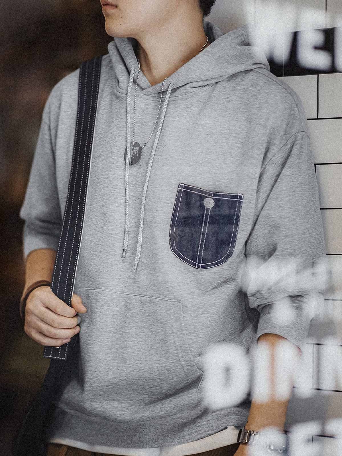 詳細画像:
「霜降り模様のコットン感ストレッチニット生地と、白いステッチと刻印入り銅製ボタンをあしらったデニムポケットのディテールクローズアップ。パッチワークデザインがヴィンテージ感と立体感を強調。」
モデル画像:
「モデルがデニムポケット付き パッチワーク パーカーを着用し、スポーティーなヴィンテージスタイルを披露。ゆったりとしたルーズフィットのシルエットが、カジュアルシーンからスポーツスタイルまで幅広く対応。」