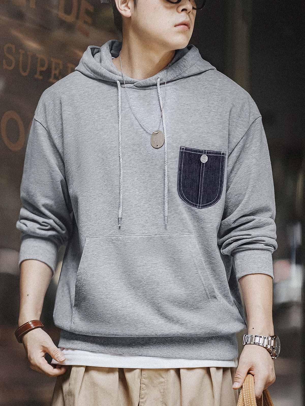 詳細画像:
「霜降り模様のコットン感ストレッチニット生地と、白いステッチと刻印入り銅製ボタンをあしらったデニムポケットのディテールクローズアップ。パッチワークデザインがヴィンテージ感と立体感を強調。」
モデル画像:
「モデルがデニムポケット付き パッチワーク パーカーを着用し、スポーティーなヴィンテージスタイルを披露。ゆったりとしたルーズフィットのシルエットが、カジュアルシーンからスポーツスタイルまで幅広く対応。」