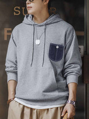 詳細画像:
「霜降り模様のコットン感ストレッチニット生地と、白いステッチと刻印入り銅製ボタンをあしらったデニムポケットのディテールクローズアップ。パッチワークデザインがヴィンテージ感と立体感を強調。」
モデル画像:
「モデルがデニムポケット付き パッチワーク パーカーを着用し、スポーティーなヴィンテージスタイルを披露。ゆったりとしたルーズフィットのシルエットが、カジュアルシーンからスポーツスタイルまで幅広く対応。」