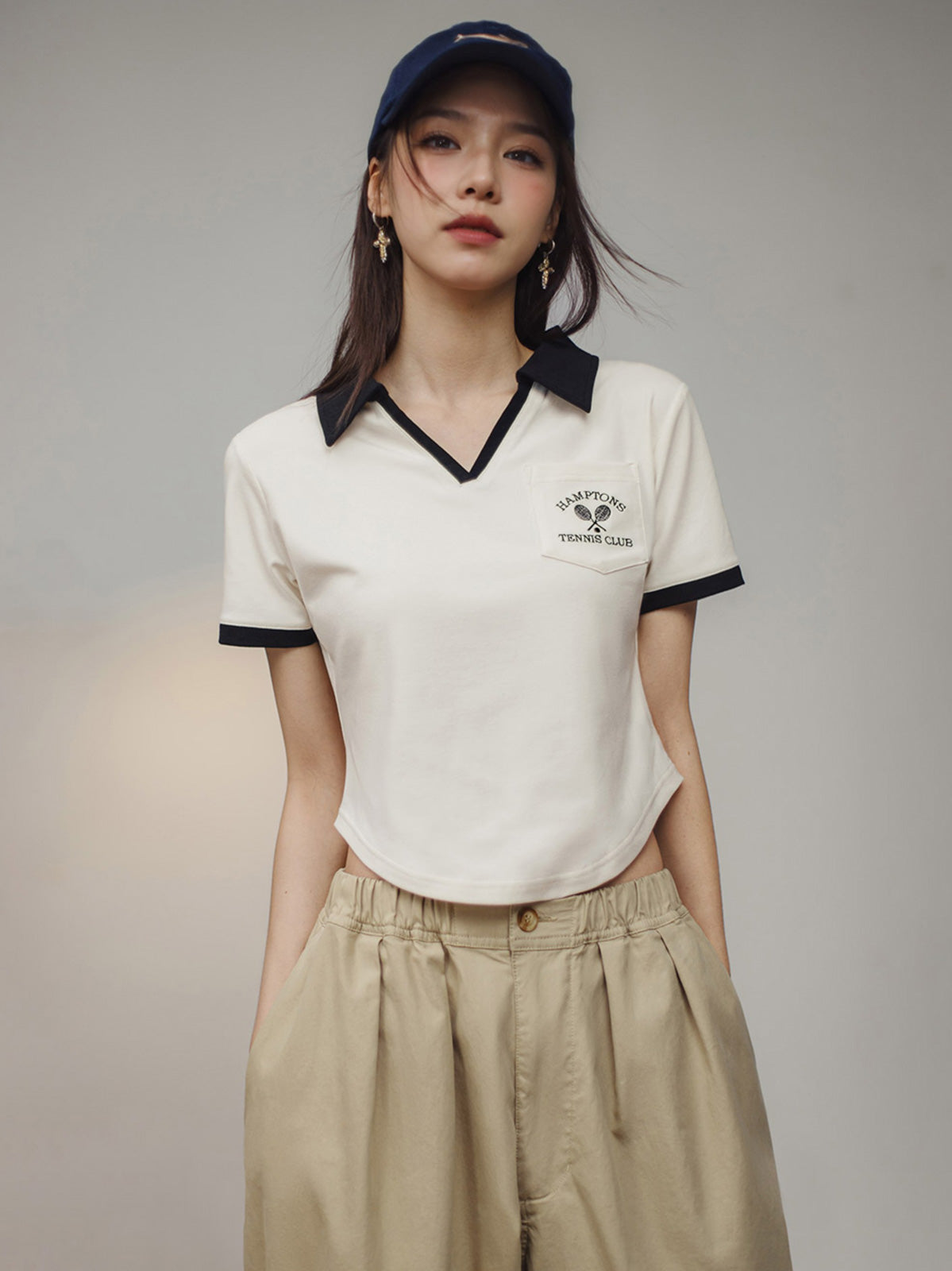 モデルがブラック&ホワイトVネックポロシャツを着用し、カジュアルかつエレガントなスタイルを披露。