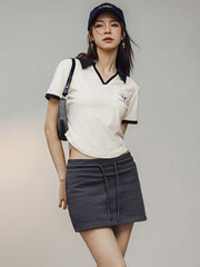 モデルがブラック&ホワイトVネックポロシャツを着用し、カジュアルかつエレガントなスタイルを披露。