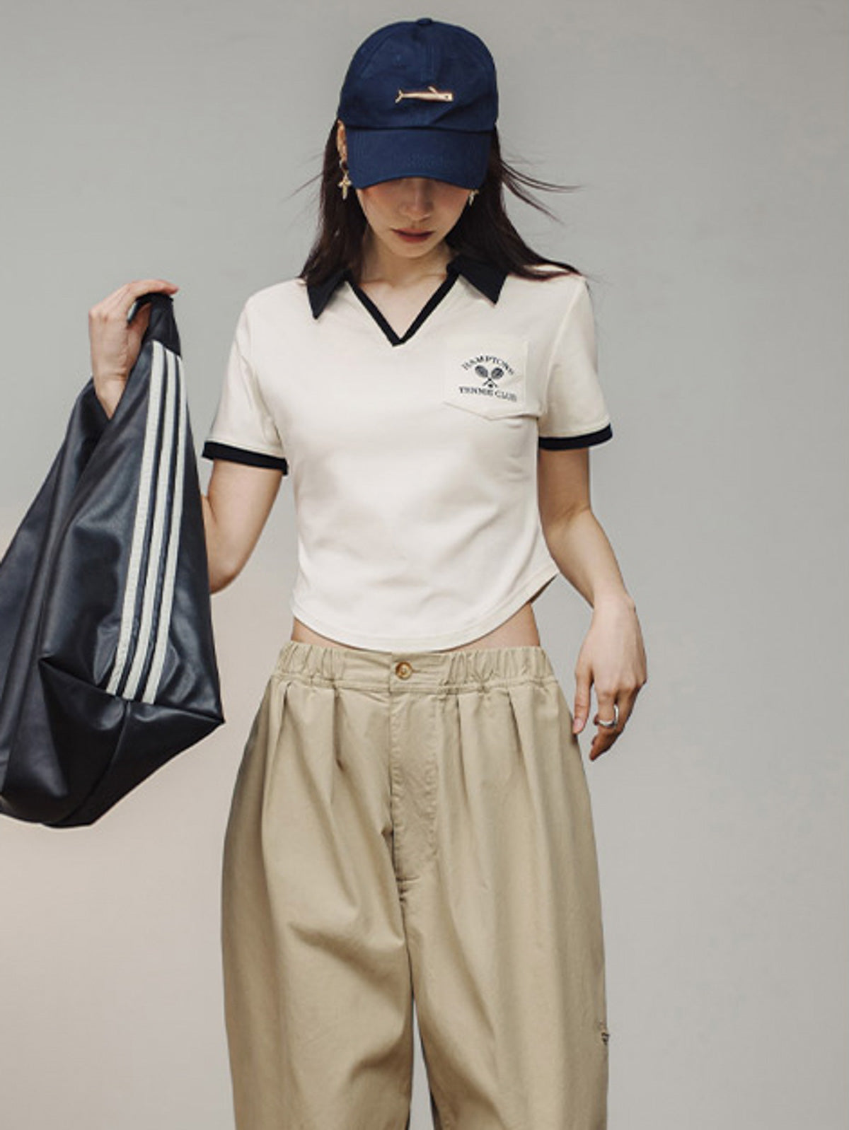 モデルがブラック&ホワイトVネックポロシャツを着用し、カジュアルかつエレガントなスタイルを披露。