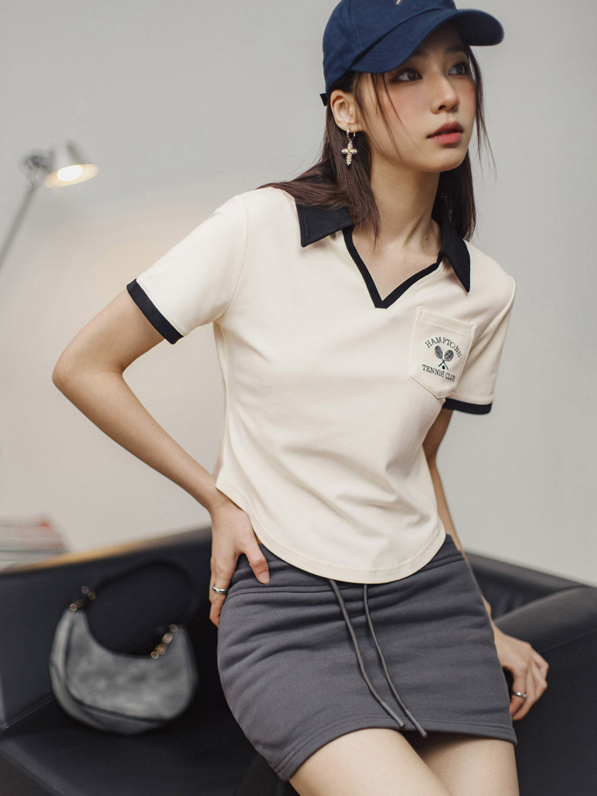 モデルがブラック&ホワイトVネックポロシャツを着用し、カジュアルかつエレガントなスタイルを披露。