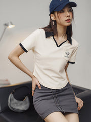 モデルがブラック&ホワイトVネックポロシャツを着用し、カジュアルかつエレガントなスタイルを披露。