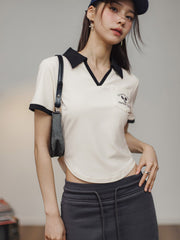 モデルがブラック&ホワイトVネックポロシャツを着用し、カジュアルかつエレガントなスタイルを披露。