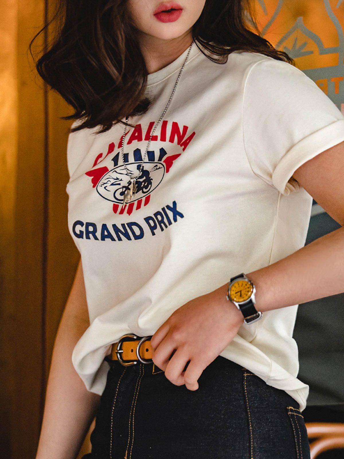 モデルがカタリナ・グランプリ モーターサイクルレースプリントTシャツを着用し、カジュアルスタイルを披露。