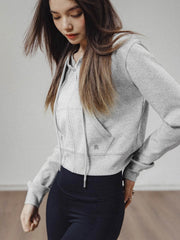 モデルがアメリカンストリートスタイルのグレーショート丈フーディージップアップを着用し、多様なスタイリングを披露