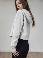 モデルがアメリカンストリートスタイルのグレーショート丈フーディージップアップを着用し、多様なスタイリングを披露