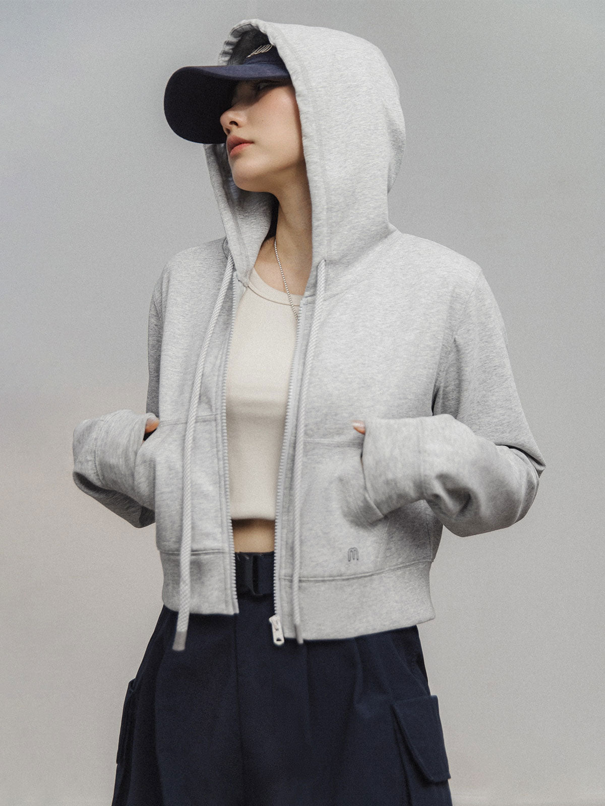 モデルがアメリカンストリートスタイルのグレーショート丈フーディージップアップを着用し、多様なスタイリングを披露