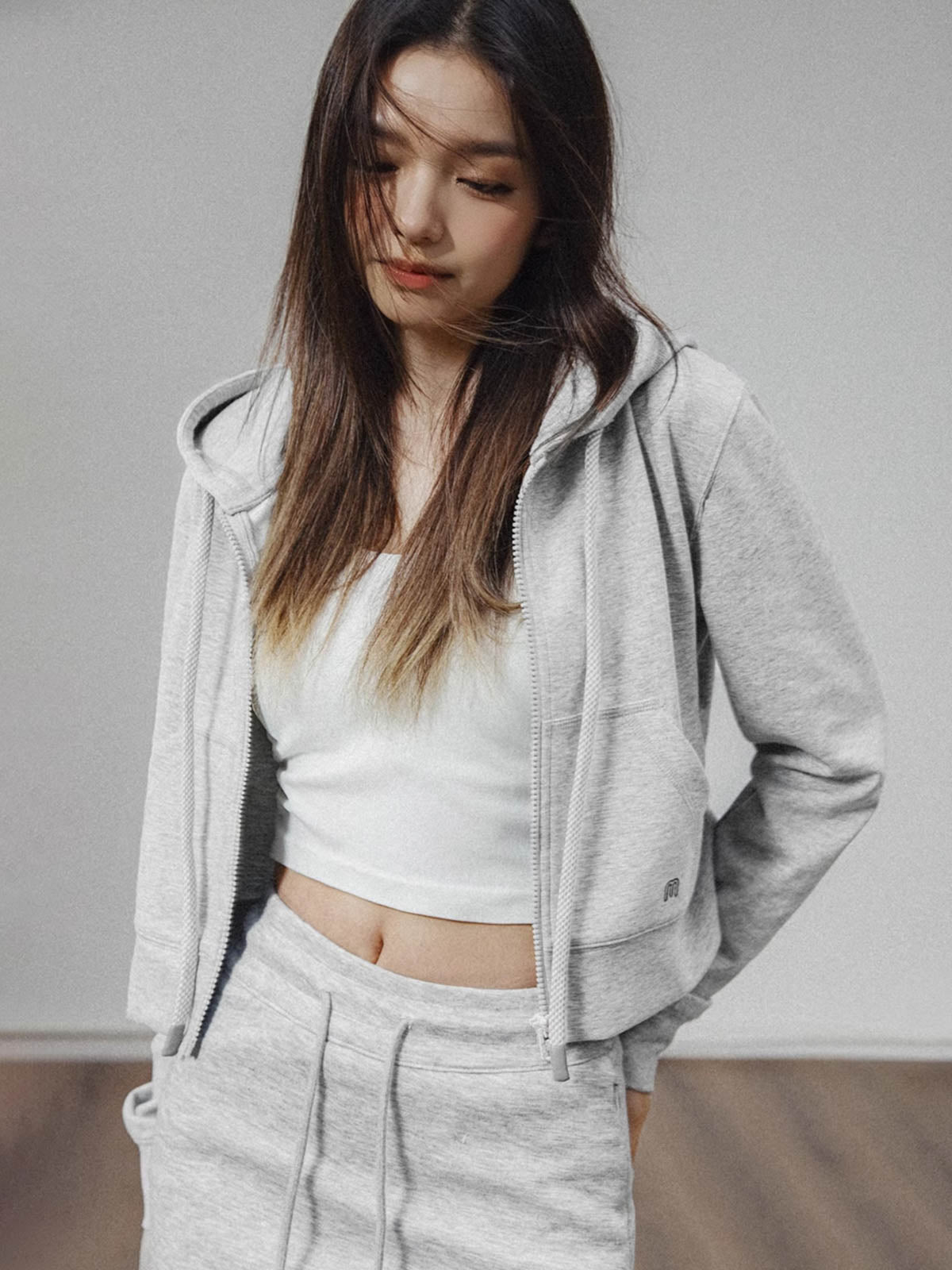 モデルがアメリカンストリートスタイルのグレーショート丈フーディージップアップを着用し、多様なスタイリングを披露