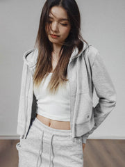 モデルがアメリカンストリートスタイルのグレーショート丈フーディージップアップを着用し、多様なスタイリングを披露