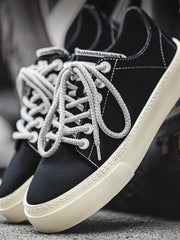 製品画像
「ブラック×ホワイトのクラシックな配色デザインが特徴の厚底キャンバススニーカー側面全体画像。スエードアッパーとキャンバスつま先の異素材コンビ仕様。」
詳細画像
「スエードアッパーとキャンバスつま先の異素材コンビデザイン、ダブルステッチ縁取り、加厚ラバーソールのディテールをクローズアップ。」