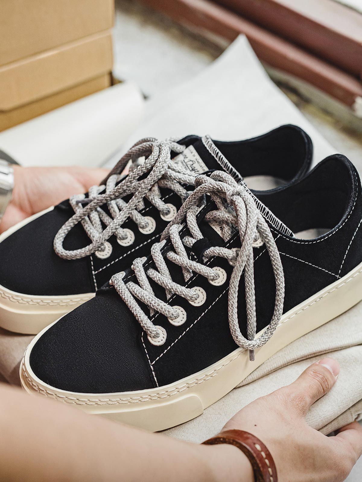 製品画像
「ブラック×ホワイトのクラシックな配色デザインが特徴の厚底キャンバススニーカー側面全体画像。スエードアッパーとキャンバスつま先の異素材コンビ仕様。」
詳細画像
「スエードアッパーとキャンバスつま先の異素材コンビデザイン、ダブルステッチ縁取り、加厚ラバーソールのディテールをクローズアップ。」