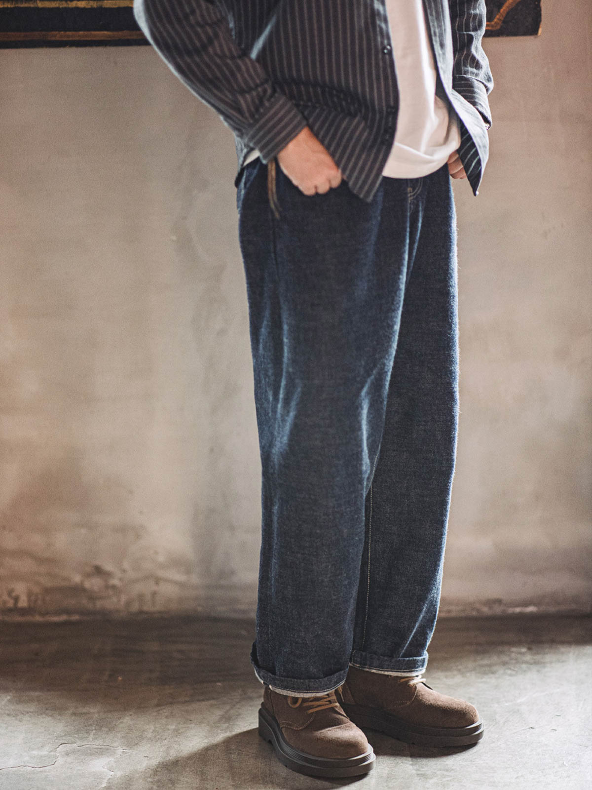 詳細画像:
ダークブラウンスエードレザーの靴に、耐久性を高める洗い加工したキャンバスを使用。しっかりとした靴筒と履き口のデザイン、手縫いのマークスティッチ、上部の牛革タグが特徴。
モデル画像:
ワイルドライフ風ダークブラウンスエード作業靴の着用イメージ。1960年代マーチンブーツをインスパイアしたデザインで、実用性とファッション性を兼ね備えたアイテム。