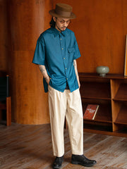 モデルがフラップポケットプリント半袖シャツを着用し、ライトカラーのパンツとコーディネート