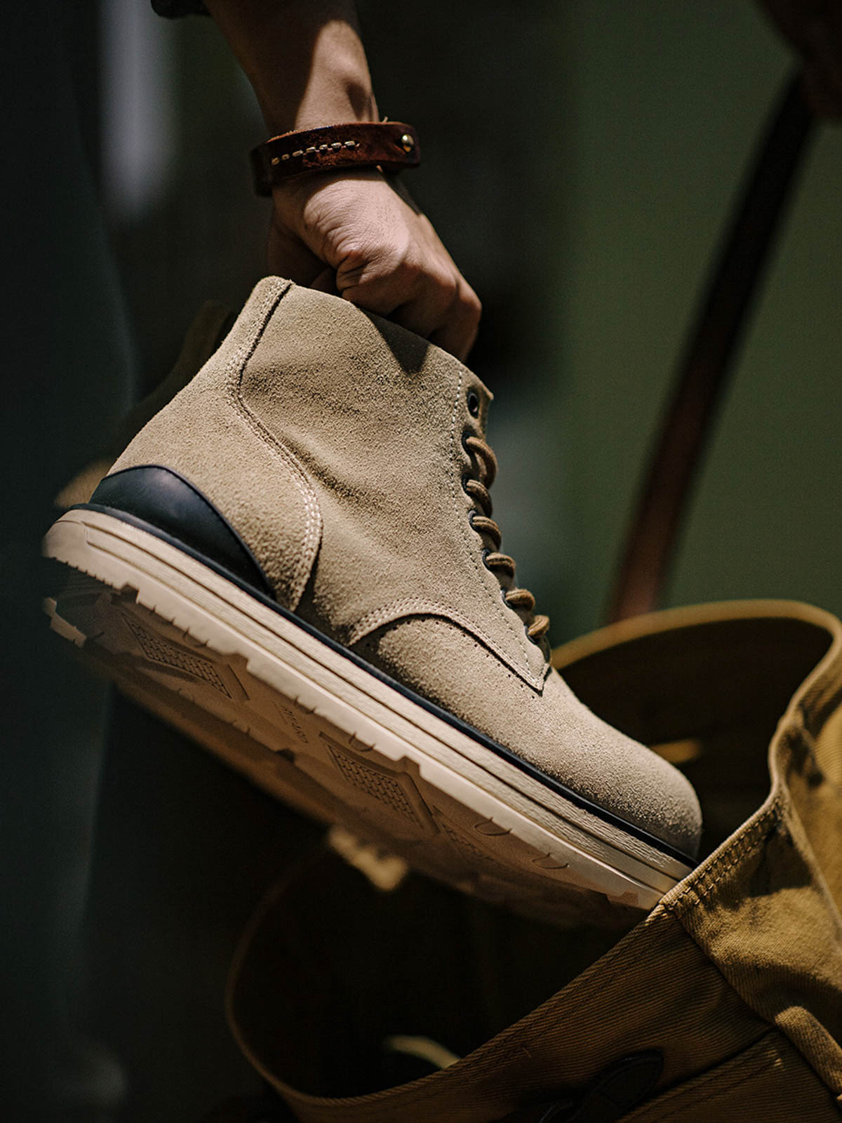 製品画像: 厳選された牛革スエードと特注厚底デザインを組み合わせたヴィンテージ感漂うワークブーツ全体像、グラベルカラーのトーンが特徴。
詳細画像: 牛革スエードのアッパー、PUレザー靴舌、白いステッチが際立つラバーディテールのクローズアップ。